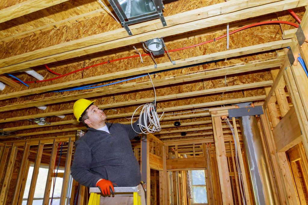 Electrician installing wiring in a new home construction.